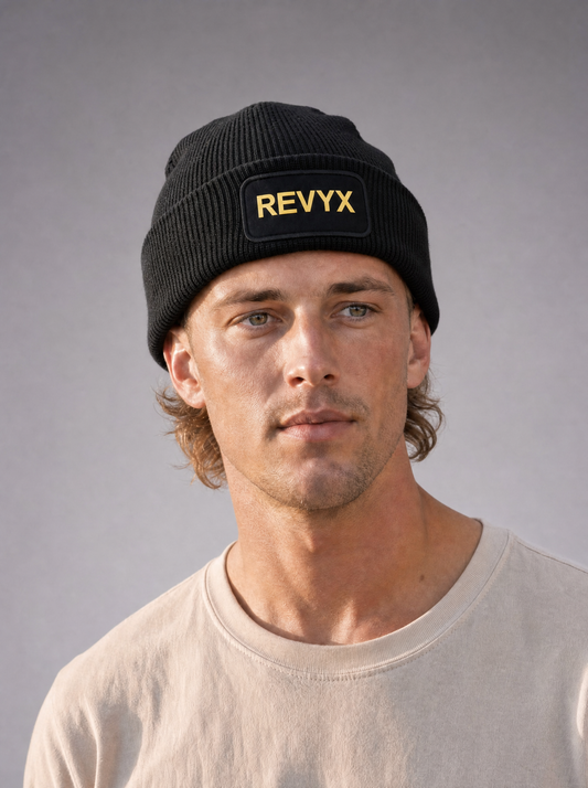 REVYX Core Beanie - Schräge Nahaufnahme, getragen von männlichem Model, schwarze Strickmütze mit gelbem "REVYX"-Logo-Patch [KI]