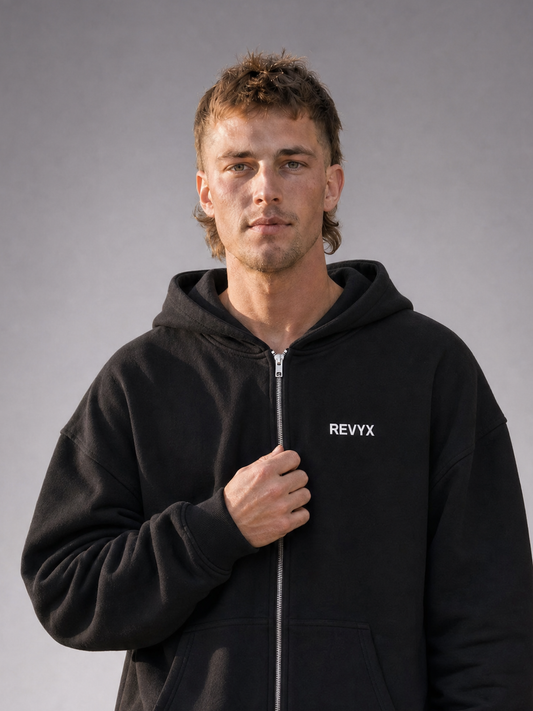 WINGMAN Zip Hoodie black - Nahaufnahme Frontansicht, getragen von männlichem Model, mit kleinem weißen "REVYX"-Schriftzug auf der Brust [KI]